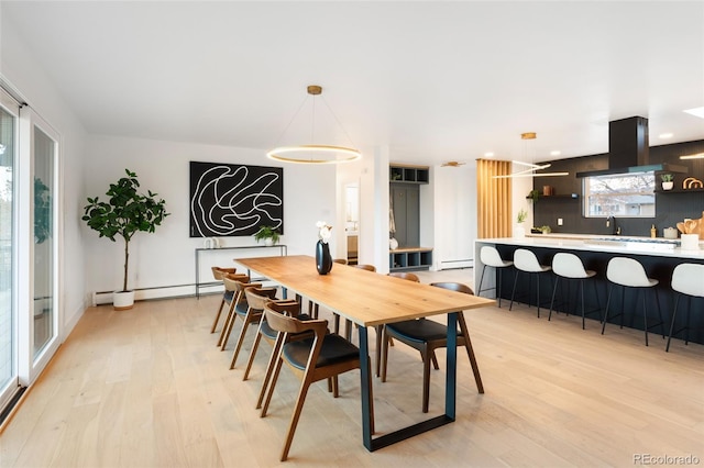 dining room with baseboard heating and light hardwood / wood-style flooring