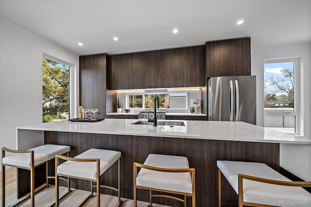 kitchen featuring sink, kitchen peninsula, stainless steel fridge, and a healthy amount of sunlight