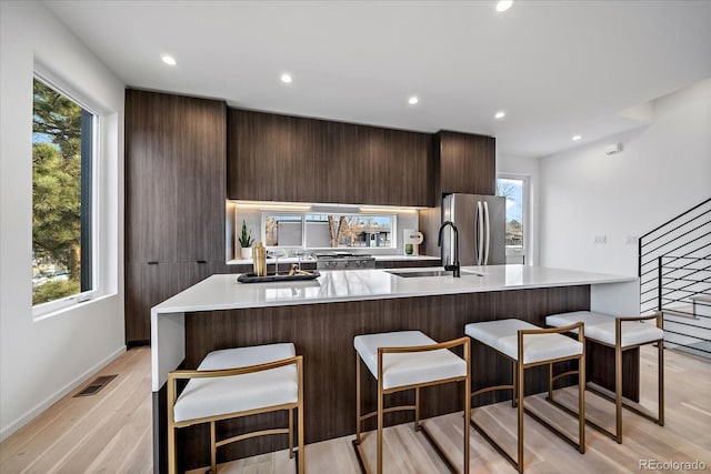 kitchen featuring sink, a kitchen bar, stainless steel refrigerator, and a healthy amount of sunlight