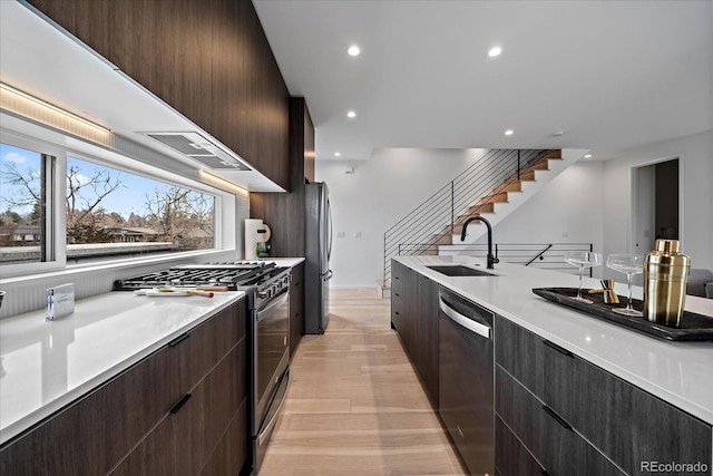 kitchen with light wood-type flooring, appliances with stainless steel finishes, sink, and dark brown cabinetry