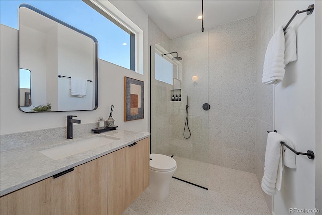 bathroom featuring toilet, a tile shower, and vanity