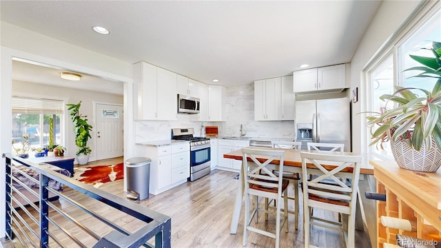 1741 W 55th Pl, Denver, CO 80221 - kitchen featuring stainless steel appliances, backsplash, white cabinetry, recessed lighting, and light wood-type flooring