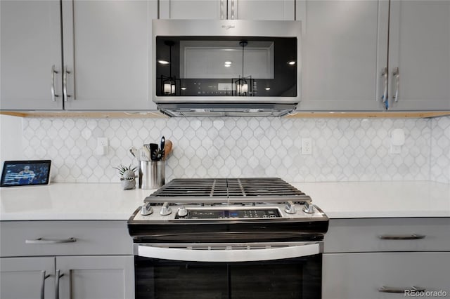 kitchen with decorative backsplash, stainless steel appliances, light countertops, and gray cabinetry