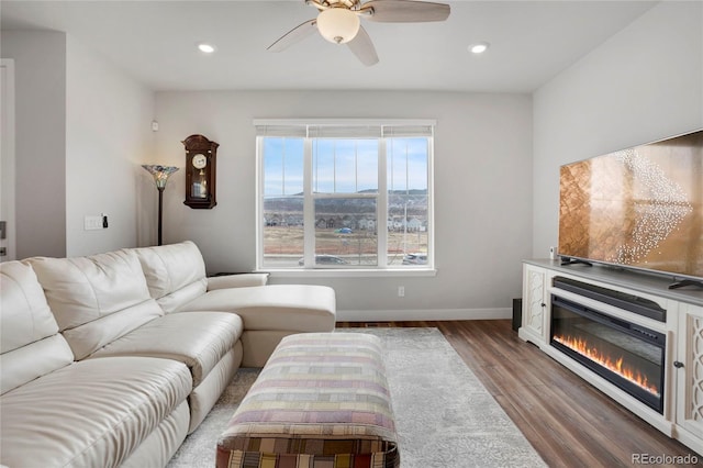 living room with ceiling fan, recessed lighting, wood finished floors, baseboards, and a glass covered fireplace