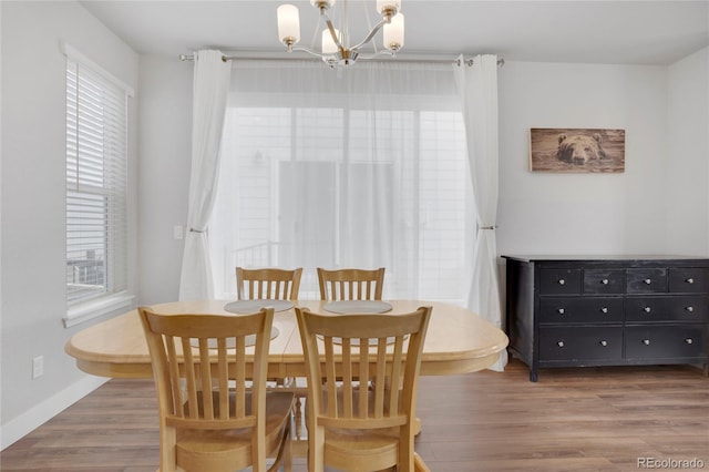 dining area featuring a chandelier, baseboards, and wood finished floors