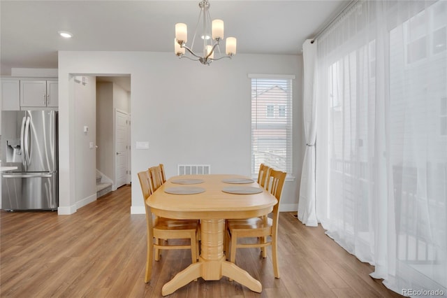 dining area with light wood-style floors, baseboards, stairway, and visible vents