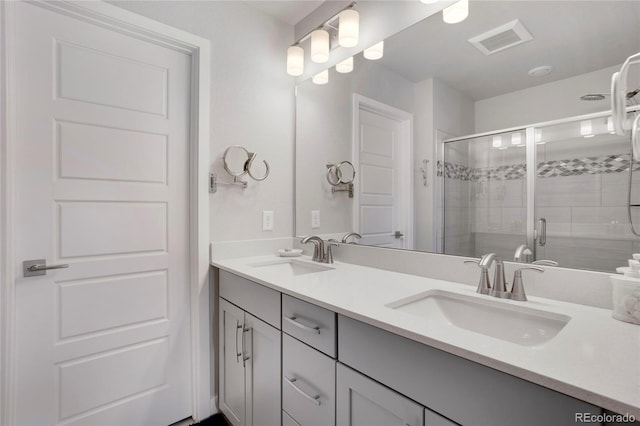 bathroom with double vanity, a stall shower, visible vents, and a sink