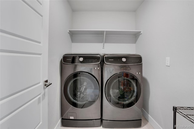 clothes washing area with washing machine and dryer, laundry area, and baseboards