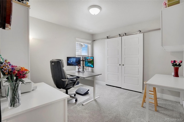 office featuring baseboards, a barn door, and light colored carpet