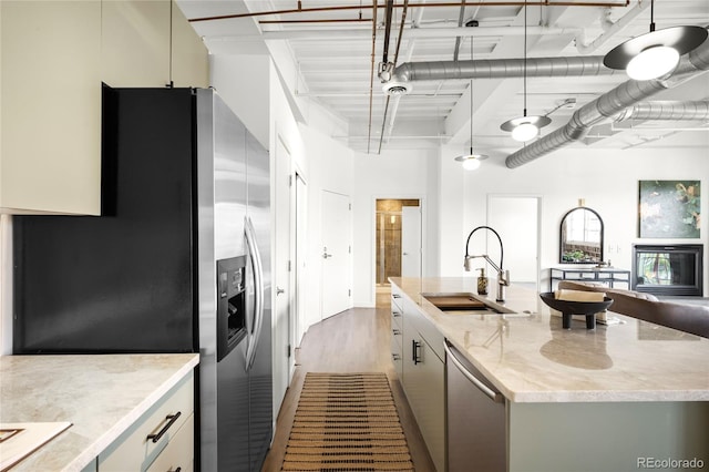1435 Wazee St Unit 305, Denver, CO 80202 - kitchen with a sink, stainless steel appliances, an island with sink, wood finished floors, and light stone counters