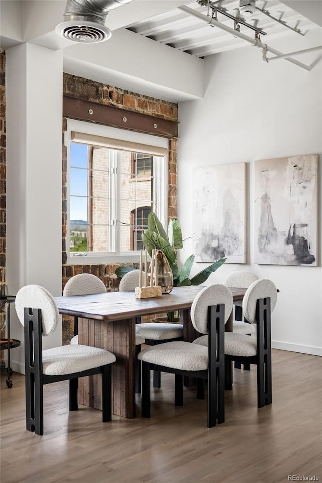 1435 Wazee St Unit 305, Denver, CO 80202 - dining space with wood finished floors, beamed ceiling, baseboards, and brick wall