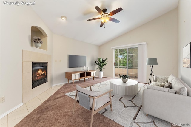 living room with high vaulted ceiling, ceiling fan, a tile fireplace, and light tile patterned flooring