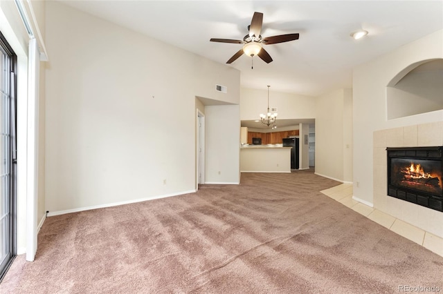 unfurnished living room with ceiling fan with notable chandelier, a fireplace, light carpet, and high vaulted ceiling