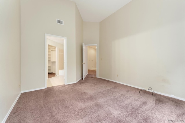 unfurnished bedroom with high vaulted ceiling, a closet, and light carpet