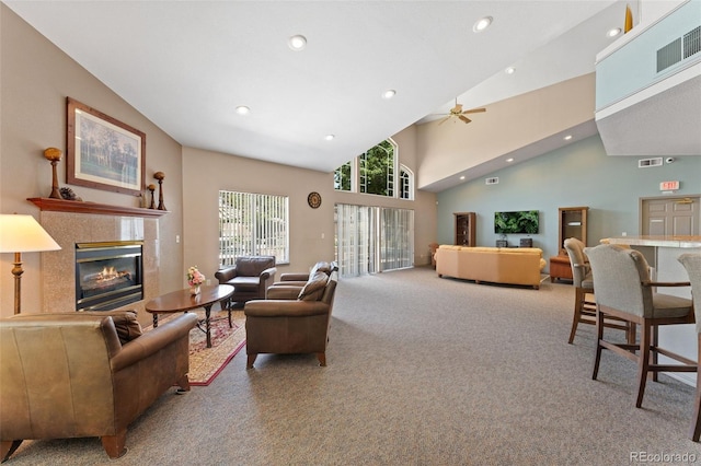 carpeted living room with ceiling fan and high vaulted ceiling