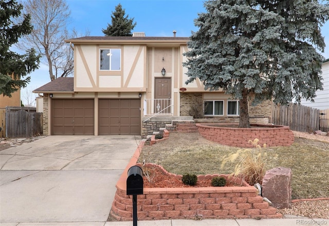 view of front of property with stucco siding, concrete driveway, a garage, and fence