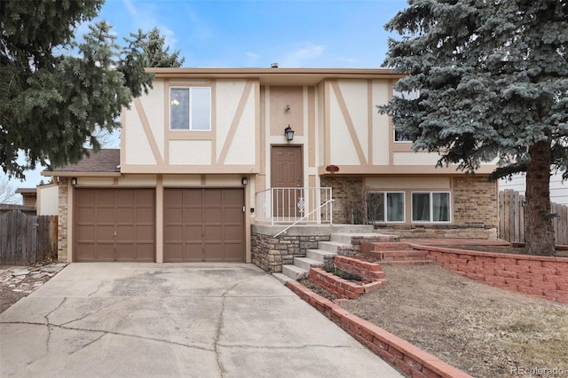 tudor house featuring stucco siding, driveway, an attached garage, and fence