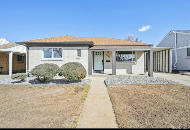 view of front of home featuring brick siding, concrete driveway, and roof with shingles