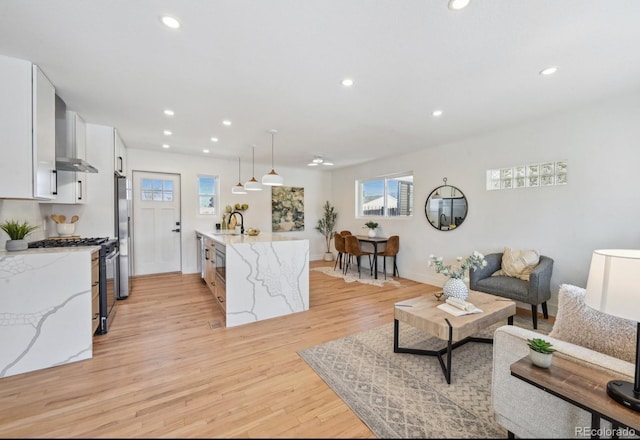 living room with recessed lighting, light wood-style flooring, and baseboards