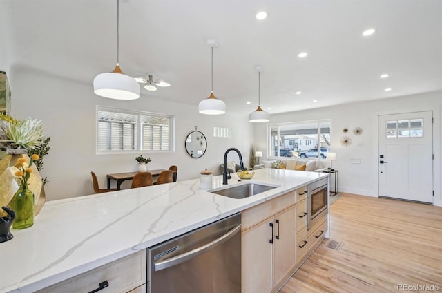 kitchen with light stone counters, recessed lighting, a sink, stainless steel appliances, and light wood-style floors