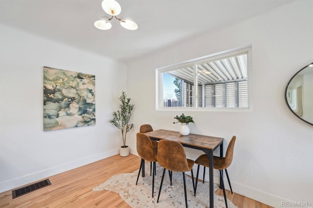 dining area featuring wood finished floors, a notable chandelier, baseboards, and visible vents