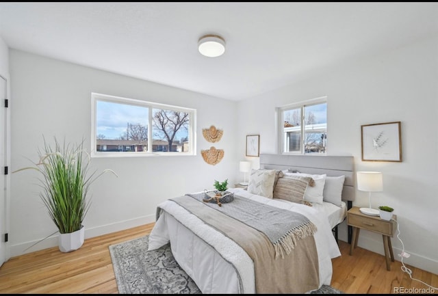 bedroom featuring baseboards, multiple windows, and wood finished floors