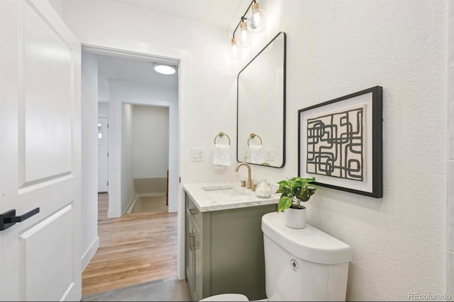 bathroom featuring toilet, wood finished floors, and vanity