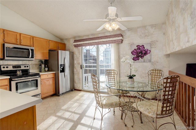 kitchen with a textured ceiling, appliances with stainless steel finishes, lofted ceiling, decorative backsplash, and ceiling fan