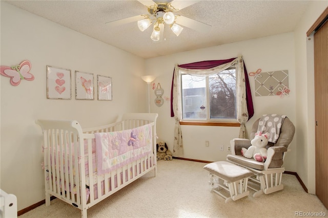 carpeted bedroom featuring ceiling fan, a textured ceiling, and a crib