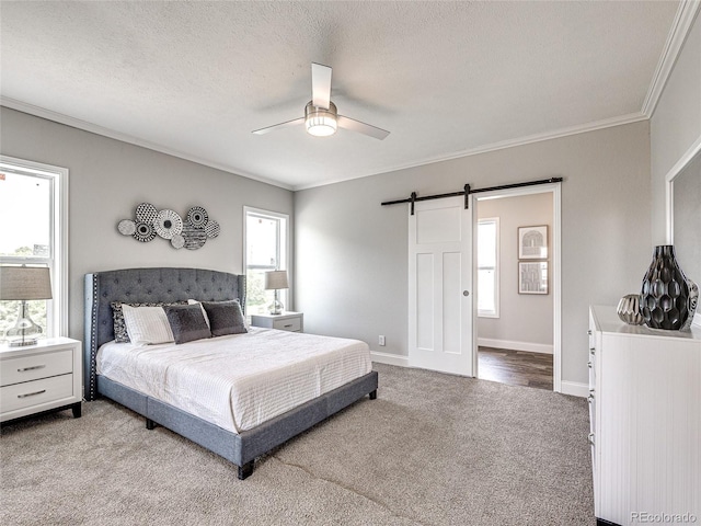 bedroom featuring ceiling fan, ornamental molding, a barn door, and carpet floors