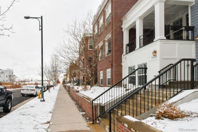 view of snowy exterior with brick siding