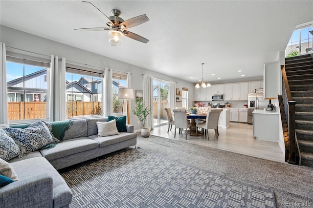 living area featuring stairs, recessed lighting, and ceiling fan with notable chandelier