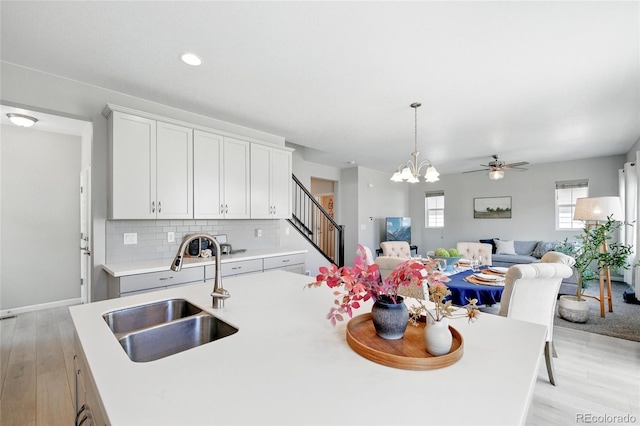 kitchen featuring decorative backsplash, a sink, light countertops, light wood finished floors, and open floor plan