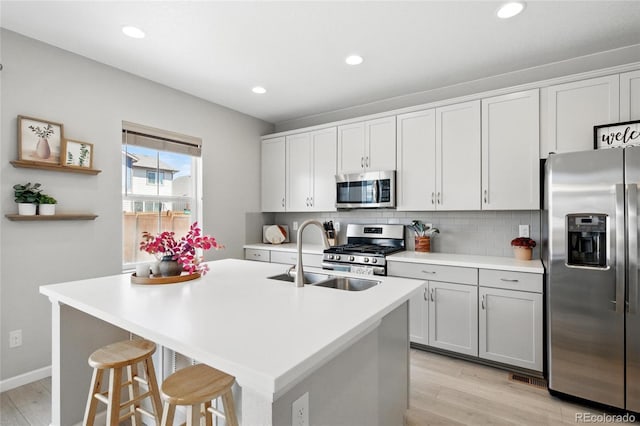 kitchen with tasteful backsplash, a sink, stainless steel appliances, recessed lighting, and light wood-type flooring