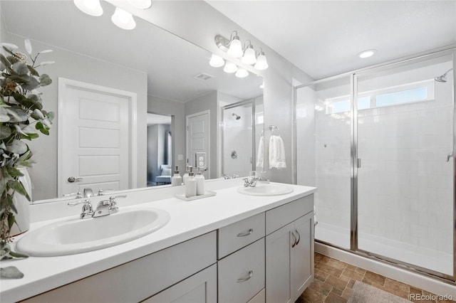 full bathroom featuring double vanity, stone finish floor, a sink, and a stall shower