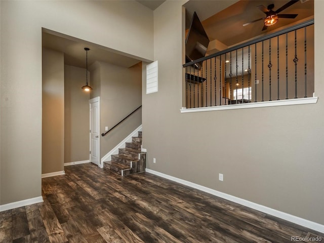 stairway featuring ceiling fan, a towering ceiling, and wood-type flooring