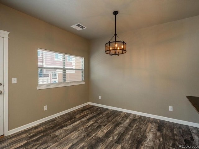 unfurnished dining area with dark hardwood / wood-style floors and an inviting chandelier