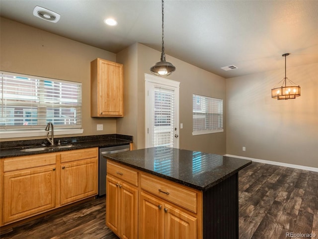 kitchen with dishwasher, sink, dark wood-type flooring, dark stone countertops, and decorative light fixtures