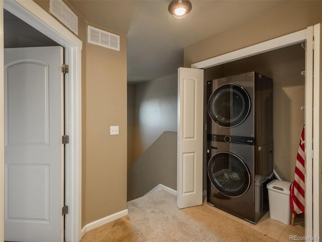 laundry room featuring light colored carpet and stacked washer / dryer