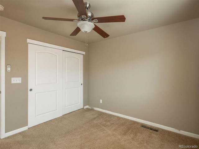 unfurnished bedroom featuring ceiling fan, a closet, and light carpet