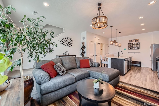 living area with light wood-style floors, a notable chandelier, visible vents, and recessed lighting