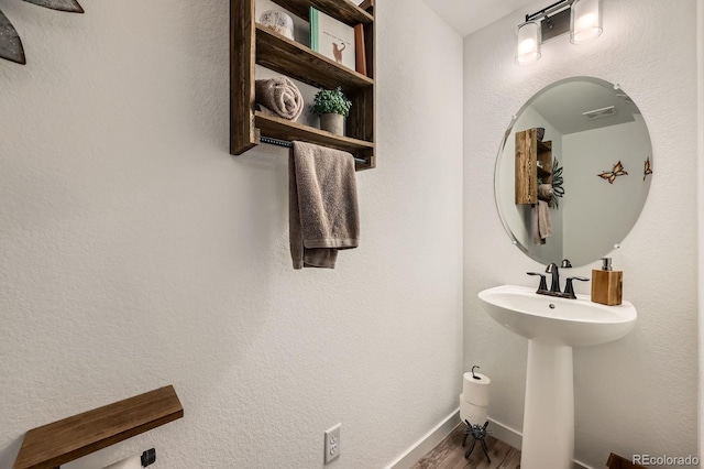 bathroom with a sink, baseboards, visible vents, and wood finished floors