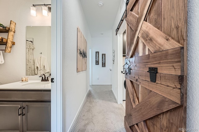 hallway with carpet, baseboards, and a sink