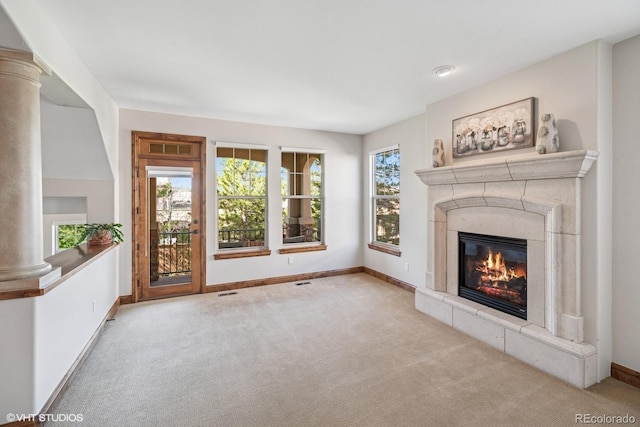 unfurnished living room with a fireplace, baseboards, carpet, and ornate columns