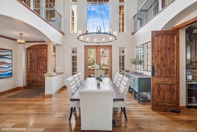 dining area with wood-type flooring, arched walkways, beverage cooler, and french doors