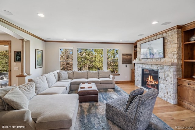 living area featuring recessed lighting, light wood-style flooring, crown molding, and decorative columns