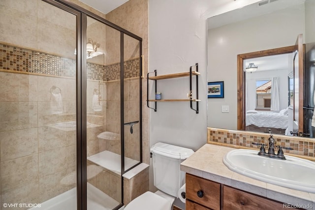 ensuite bathroom with toilet, a stall shower, ensuite bathroom, decorative backsplash, and vanity