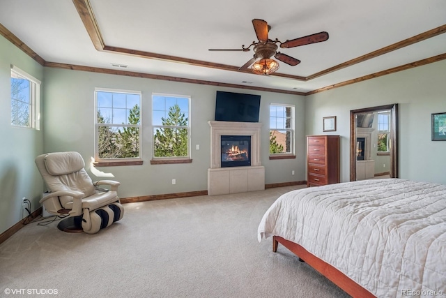 bedroom with a glass covered fireplace, carpet floors, a raised ceiling, and crown molding