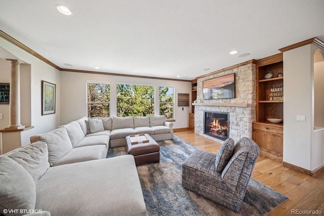 living room featuring light wood-style floors, decorative columns, a fireplace, ornamental molding, and recessed lighting