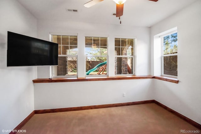 interior space featuring baseboards, a ceiling fan, visible vents, and carpet